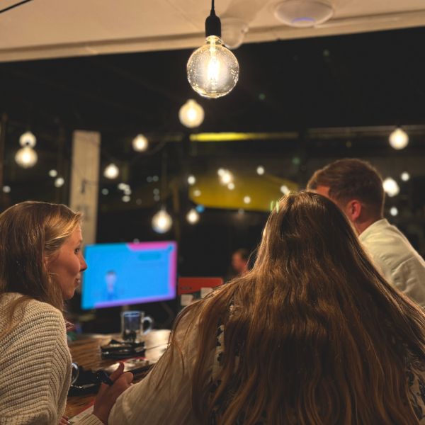 Teams in een café kijken naar het scherm tijdens een pubquiz
