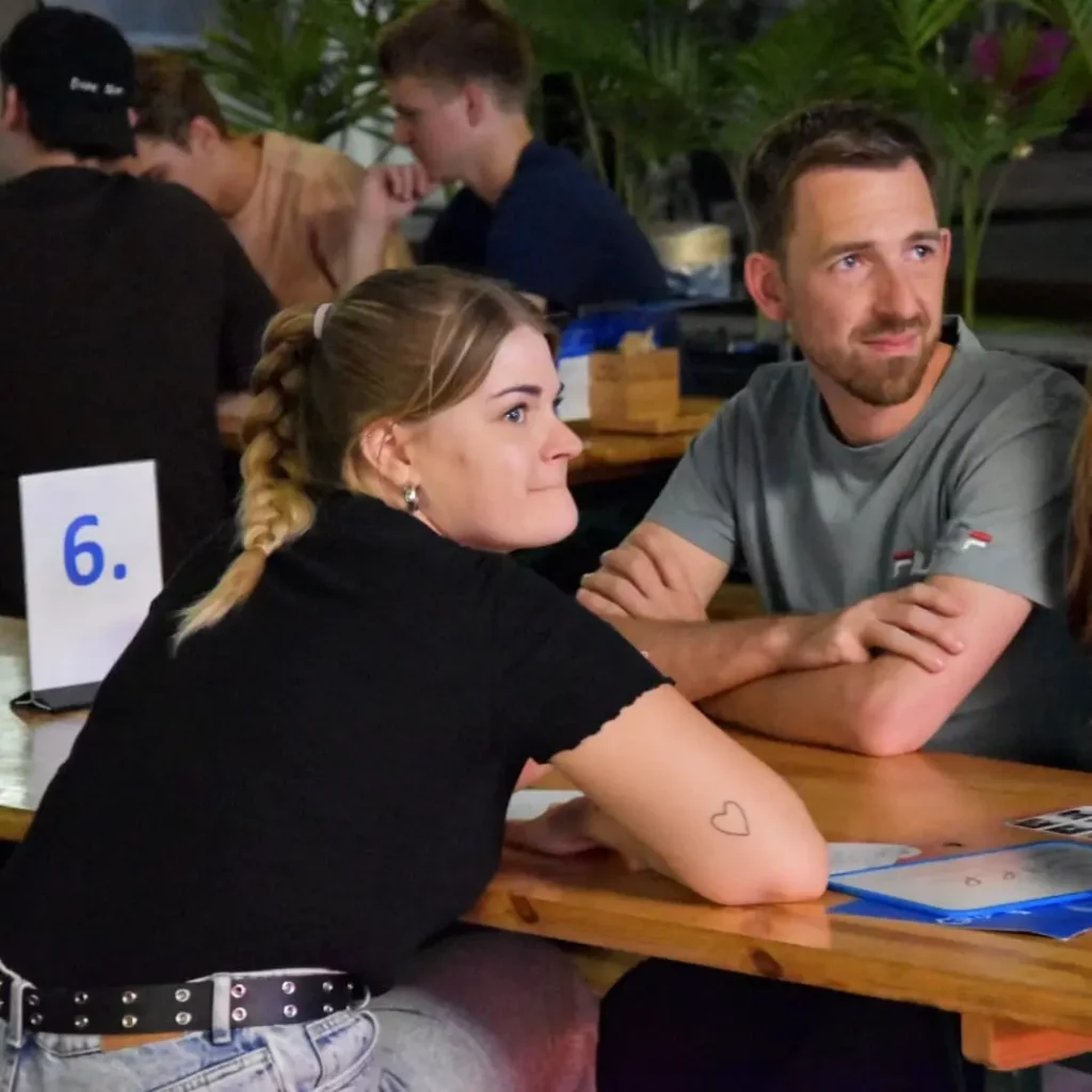 Quizteam overlegt over een antwoord tijdens een pubquiz op locatie
